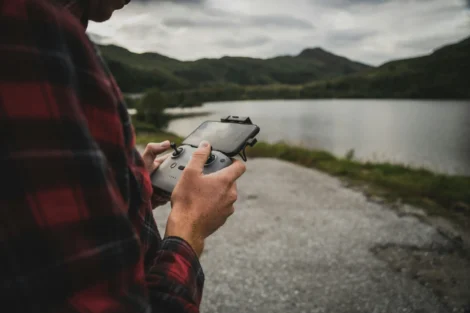 photo of advanced GIS mapping via drones pilot operating drone controller near lake survey site