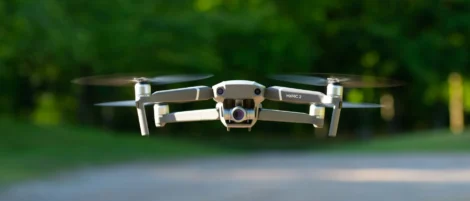 DJI Mavic 2 drone hovering at eye level on a tree-lined path outdoors