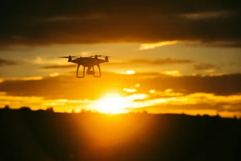 Image of a drone silhouette flying against a golden sunset sky