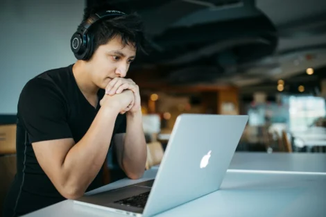Person wearing headphones studying at a MacBook in a café