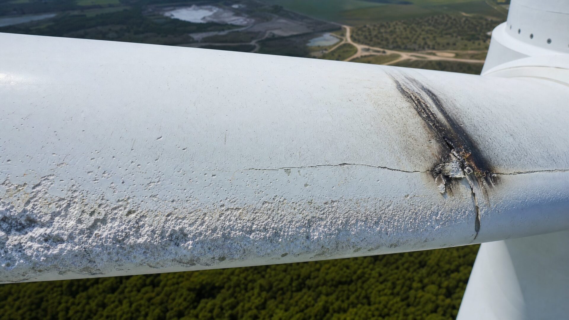 Close-up of wind turbine blade showing leading edge erosion and lightning strike damage