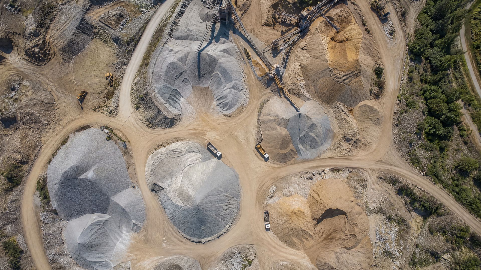 Aerial drone survey orthomosaic of mining quarry with aggregate stockpiles and heavy equipment